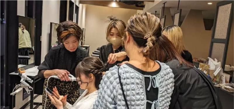 美容師たちがサロンでお客様のヘアスタイルを整えている様子