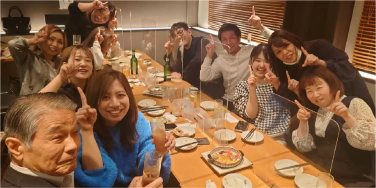 食事会で楽しそうにポーズを取りながら写真を撮っている美容師たち