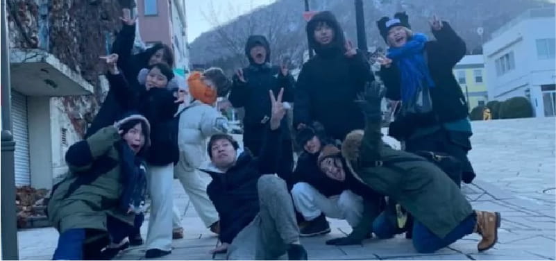 冬の街で笑顔の集合写真を撮っている美容師たち